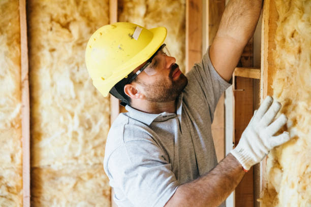 Construction worker fitting insulation in wooden house frame